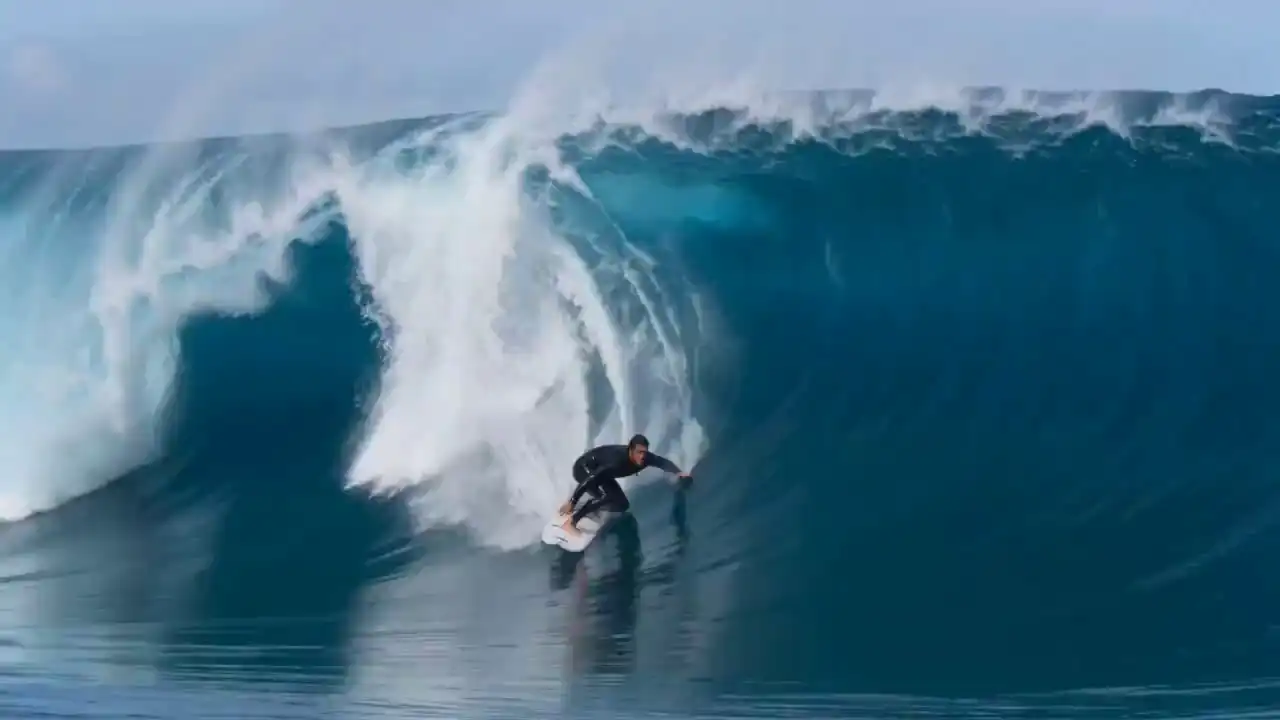 A professional surfer rides through a massive blue wave tunnel in cinematic slow motion, captured by Seedance 2.0.